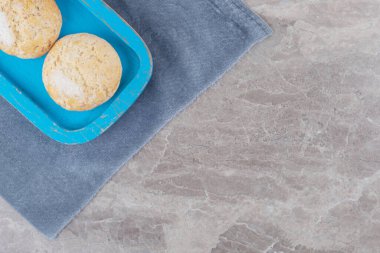 Mavi bir tepside mermer arkaplandaki kumaş parçasında parçalanmış kurabiyeler. Yüksek kalite fotoğraf