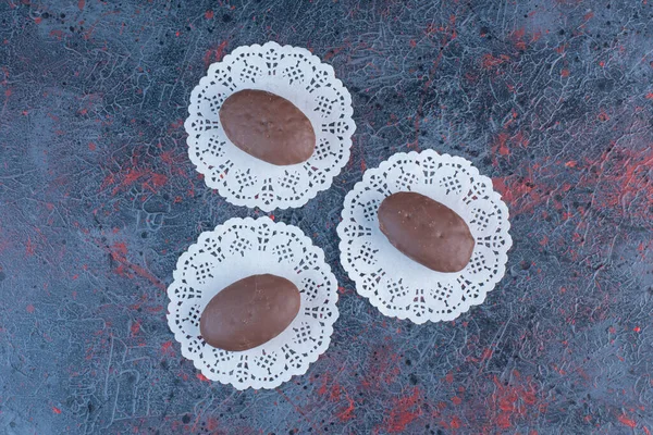 Chocolate coated cakes on doilies on abstract background. High quality photo