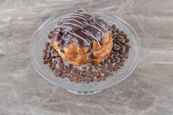 Glass platter with coffee beans chocolate coated cake on marble background. High quality photo