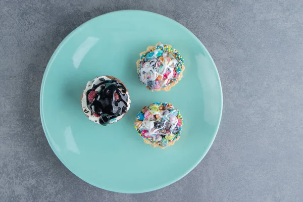 Een Blauwe Plaat Van Drie Zoete Cupcakes Met Hagelslag Hoge — Stockfoto