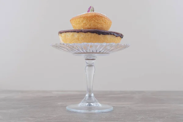 Chocolate cake and vanilla powder topped cake stacked on a glass pedestal on marble background. High quality photo