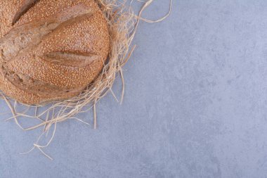 Mermer zemin üzerinde saman yığını üzerinde duran tek bir ekmek somunu. Yüksek kalite fotoğraf