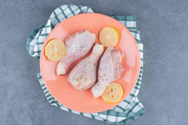Çiğ tavuk budu ve turuncu tabakta limon. Yüksek kalite fotoğraf