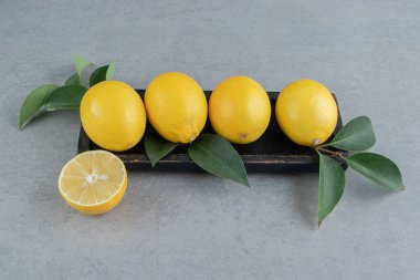 Limonlar mermer arka planda yapraklarla süslenmiş küçük bir tepside. Yüksek kalite fotoğraf