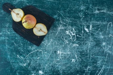 Masanın üzerinde olgun armut parçaları var, mavi arkaplanda. Yüksek kalite fotoğraf