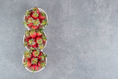 Beyaz kaselerde lezzetli olgun çilekler. Yüksek kalite fotoğraf