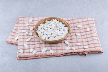 Katlanmış masa örtüsü üzerine örülmüş sepet, mermer zemin üzerinde beyaz kabak tohumlarıyla çevrili. Yüksek kalite fotoğraf