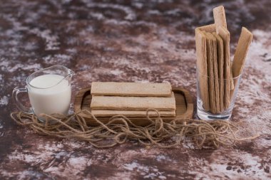 Tahta tabakta atıştırmalıklar ve krakerler ve mermerin üzerinde bir bardak süt. Yüksek kalite fotoğraf