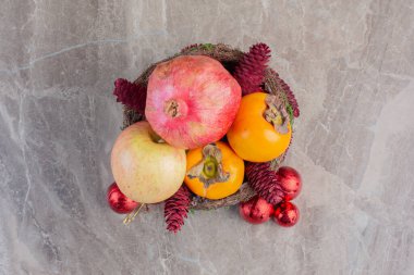 Kırmızı kozalaklı meyve sepeti ve mermer arka planda noel ağacı süslemeleri. Yüksek kalite fotoğraf