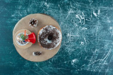 Noel süsü ve mavi arka planda çam kozalaklarıyla süslenmiş bir tahtanın üzerinde jöleli çörek. Yüksek kalite fotoğraf
