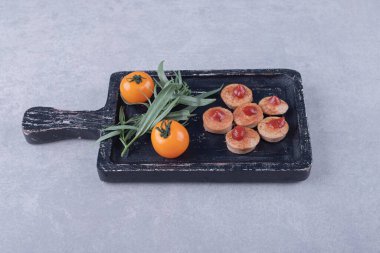 Ketçaplı dilimlenmiş sosis ve siyah tahtada domates. Yüksek kalite fotoğraf