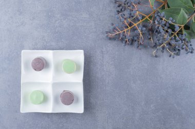 Beyaz tabakta gri arka planda renkli badem kurabiyeleri. Yüksek kalite fotoğraf