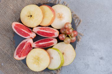 Armut ve greyfurt dilimleri, mermer zemin üzerinde tahta bir tahtanın üzerinde küçük bir üzüm kümesi. Yüksek kalite fotoğraf