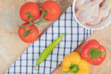 Domatesli biberler ve masa örtüsünün üstünde çiğ tavuk bacağı. Yüksek kalite fotoğraf