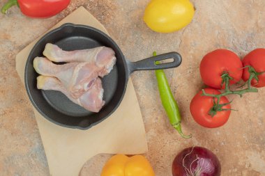 Pişmemiş tavuk bacaklı sebzeler mermer arka planda. Yüksek kalite fotoğraf