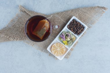 Bir fincan çayın yanında dilimlenmiş bir kase limon ve mermer zemin üzerinde havlunun üzerinde yapraklar. Yüksek kalite fotoğraf