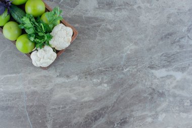 Karnabaharlı sıra sıra yeşil domatesler, salatalık, kişniş demeti ve mermer arka planda araranth yaprakları. Yüksek kalite fotoğraf