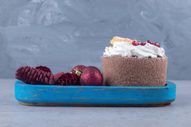 Küçük bir pastanın yanında mermer arka planda mavi bir tepside Noel süslemeleri yığını. Yüksek kalite fotoğraf