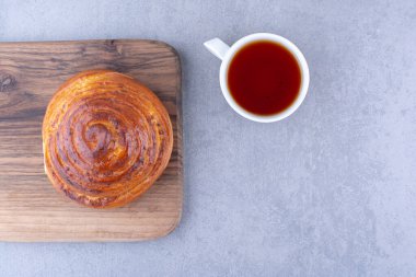 Tahtadaki tatlı çörek mermer arka planda bir fincan çayın yanında. Yüksek kalite fotoğraf