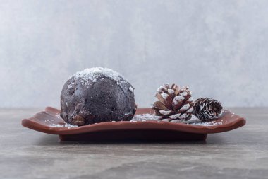 Çikolata kaplı pasta ve çam kozalakları mermer bir tabakta. Yüksek kalite fotoğraf