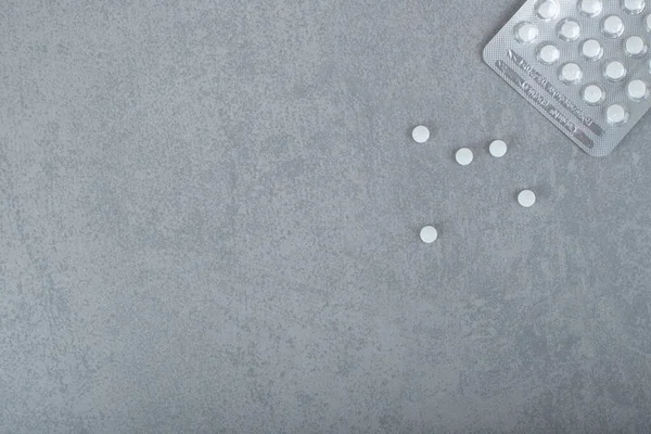 One blister with white pills on gray background. High quality photo