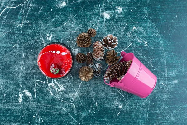 Cake next to pine cones spilled out of a bucket on blue background. High quality photo