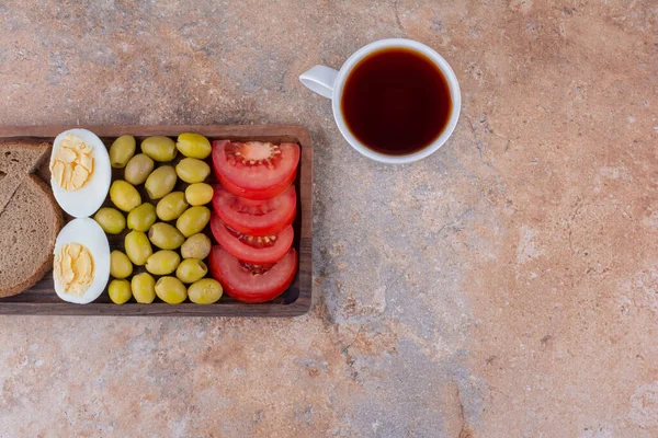 Breakfast board with bread slices, vegetable and a cup of tea. High quality photo