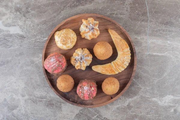 大理石の背景にトレイにクッキー カップケーキとデザートの品揃え 高品質の写真 — ストック写真
