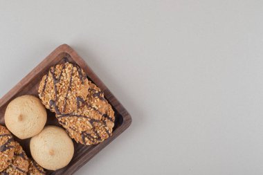 Mermer zemin üzerinde küçük bir ahşap tepside çeşitli kurabiyeler. Yüksek kalite fotoğraf