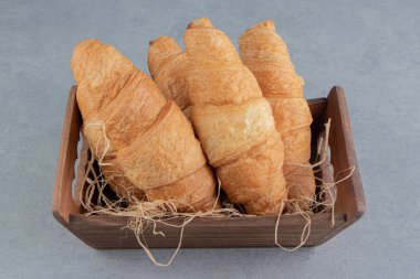 Mermer arka planda ahşap kasede kruvasanlar. Yüksek kalite fotoğraf