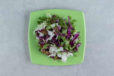 Dilimlenmiş yeşiller ve mermer zemin üzerinde bir tabakta kırmızı lahana. Yüksek kalite fotoğraf