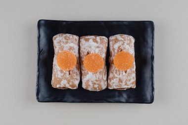 Kurabiye ambalajları ve marmelatlar mermer arka planda siyah bir tabakta. Yüksek kalite fotoğraf