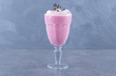 Gri arka planda taze yapılmış pembe milkshake 'in yakın plan fotoğrafı. Yüksek kalite fotoğraf