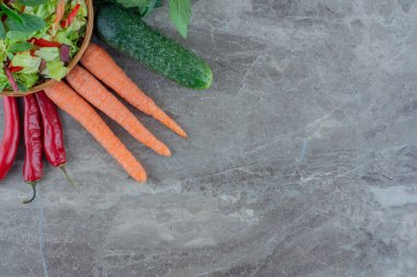 Salatalık, havuç, biber ve fesleğen yaprakları mermer arka planda bir kase salata etrafında. Yüksek kalite fotoğraf