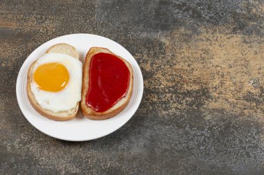 İki kızarmış ekmek, kızarmış yumurta ve beyaz tabakta reçel. Yüksek kalite fotoğraf