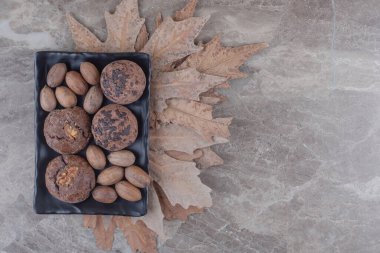 Bir tepside bir demet kurabiye ve ceviz ve mermer zemin üzerinde bir demet ağaç yaprağı. Yüksek kalite fotoğraf