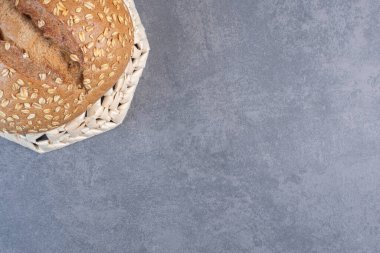 Tepetaklak bir sepetin üzerinde mermer zemin üzerinde bir somun ekmeğin üzerindeki tanecikleri kaplamak. Yüksek kalite fotoğraf
