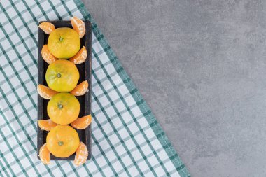 Lezzetli mandalinalar ve siyah tabakta bölümler. Yüksek kalite fotoğraf