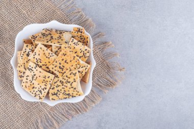 Koyu arkaplanda kimyon tohumlu tuzlu krakerler. en üstteki görünüm.