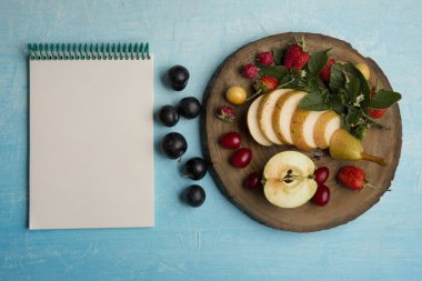 dilimlenmiş armut ve meyveler mavi mermer arka planda izole edilmiş.