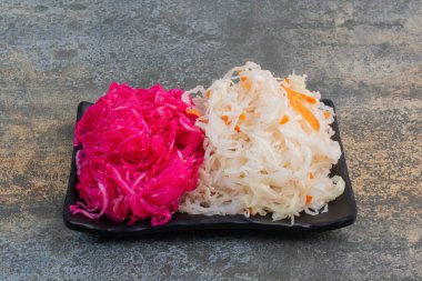 Mermer arka planda kırmızı tuzlu lahana dolu siyah bir tabak. Yüksek kalite fotoğraf