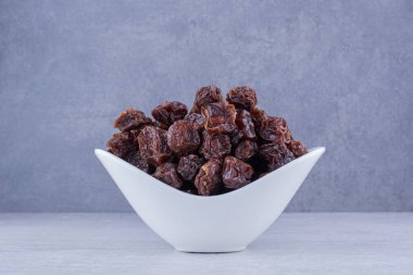 Beton arka planda izole edilmiş bir tabağın içinde kurumuş vişneli erikler. Yüksek kalite fotoğraf