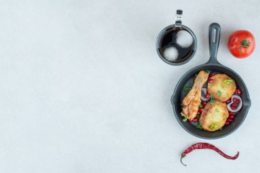 Beyaz arka planda kızarmış tavuk ve patates olan koyu bir tava. Yüksek kalite fotoğraf