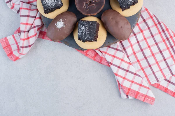 Chocolate cakes and cookies on a wooden board on marble background. High quality photo