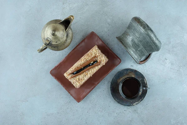 Slice of cake with cup of tea and teacup on marble surface. High quality photo