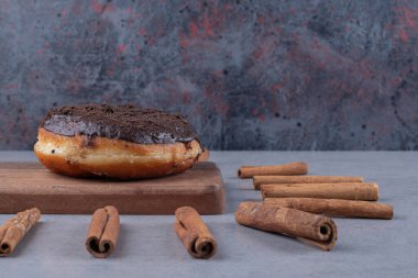 Bir çörek ve bir demet tarçın mermer zemin üzerinde çubuklar. Yüksek kalite fotoğraf