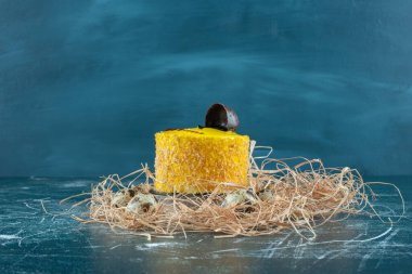 Mavi arka planda saman yığınına yerleştirilmiş küçük, sarı pasta. Yüksek kalite fotoğraf