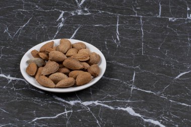 Tabakta mermer zemin üzerinde nefis kabuklu bademler var. Yüksek kalite fotoğraf