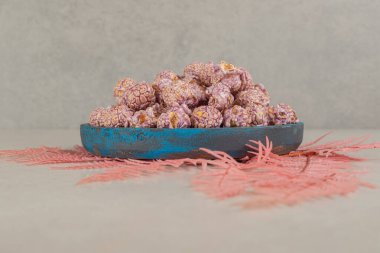 Eskimiş şeker kaplı patlamış mısır tepsisi mermer arka planda bir demet pembe yaprağın üzerinde duruyor. Yüksek kalite fotoğraf