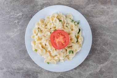 Tabakta, mermer zemin üzerinde farfalle makarnası olan domatesleri dilimle. Yüksek kalite fotoğraf